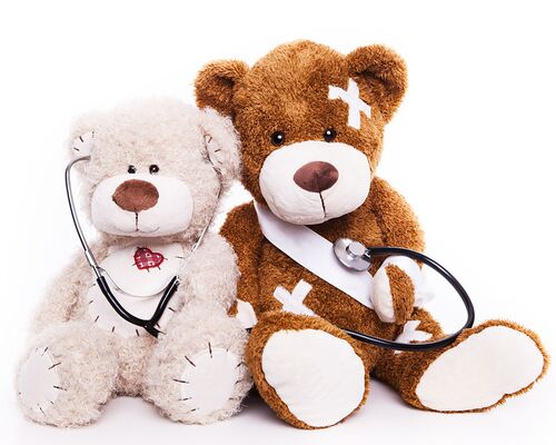 Zwei Teddy-Bären in dermatologischer Behandlung von Kindern als Patient und Arzt verkleidet. Weißer Bär untersucht mit einem Stethoskop den mit Pflastern übersäten Teddy in der Kinderdermatologie der Privatpraxis für Hautmedizin in Frankfurt am Main.