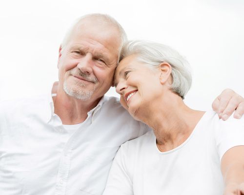 Older couple satisfied with the successful treatment of actinic keratoses (cornification disorders) in the Frankfurt private practice. Woman and man with mature wrinkled skin hug after skin treatment. They look neat.