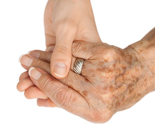 A young hand holds an older hand. The young hand has flawless healthy skin. The older hand is covered with age spots. Age spots can be permanently and painlessly removed with a ruby ​​laser.