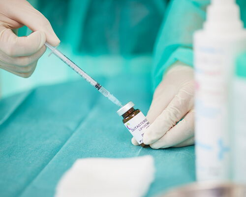Hautarzt füllt auf einem OP-Tisch eine Spritze mit Dutasterid-Flüssigkeit, um einen Patienten gegen erblich bedingten Haarausfall zu behandeln. Die folgende Injektion an der Kopfhaut wird den Verlust von Haaren hemmen und das Haarwachstum verbessern.