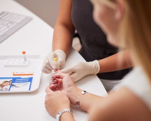 Medical assistant draws blood from a patient's index finger. Photograph of the implementation of a Prevo-Check® test for the early detection of HPV-related carcinomas for skin cancer screening in our private dermatological practice.