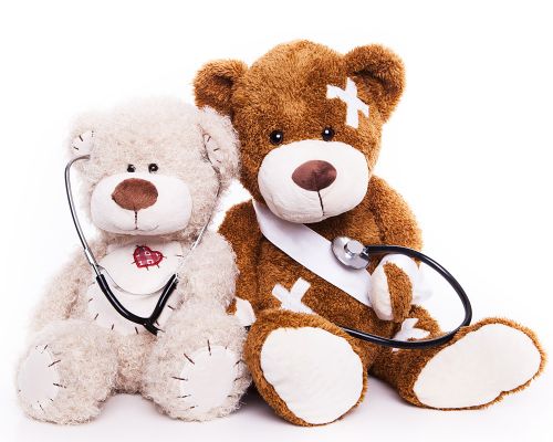 Two teddy bears dressed as a patient and doctor in dermatological treatment of children. Weißer Bär uses a stethoscope to examine the teddy covered with plasters in the pediatric dermatology department of the private practice for skin medicine in Frankfurt am Main.