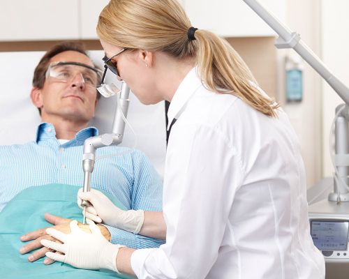 Patient undergoing medical laser treatment in the dermatology practice in Frankfurt. The patient's eyes and those of the dermatologist are protected with goggles. Doctor treats the surface of his hand with a specific laser for skin treatment.