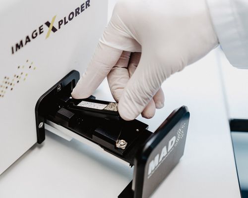 Eine Medizinische Fachangestellte bedient ein System im praxiseigenen Labor zur PCR Sequenzierung. Aus hygienischen Gründen hat die Arzthelferin sterile Handschuhe an. Das MAD-Gerät wertet das DNA-Molekühl eines Patienten für eine Allergie-Diagnose aus.