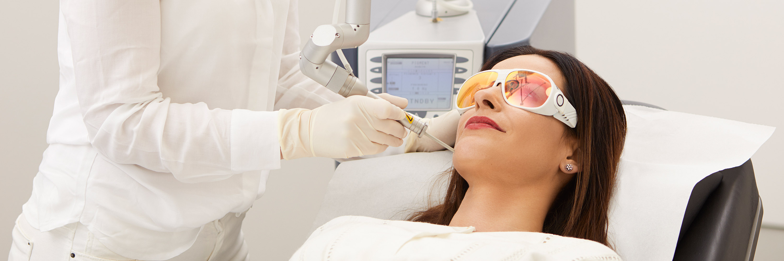 A patient is treated lying down with a modern medical laser system for skin treatments in the Frankfurt private practice. Diode lasers, Erbium-YAG lasers, lasers with fractional handpieces, KTP lasers and Ruby ​​lasers are available to specialists.