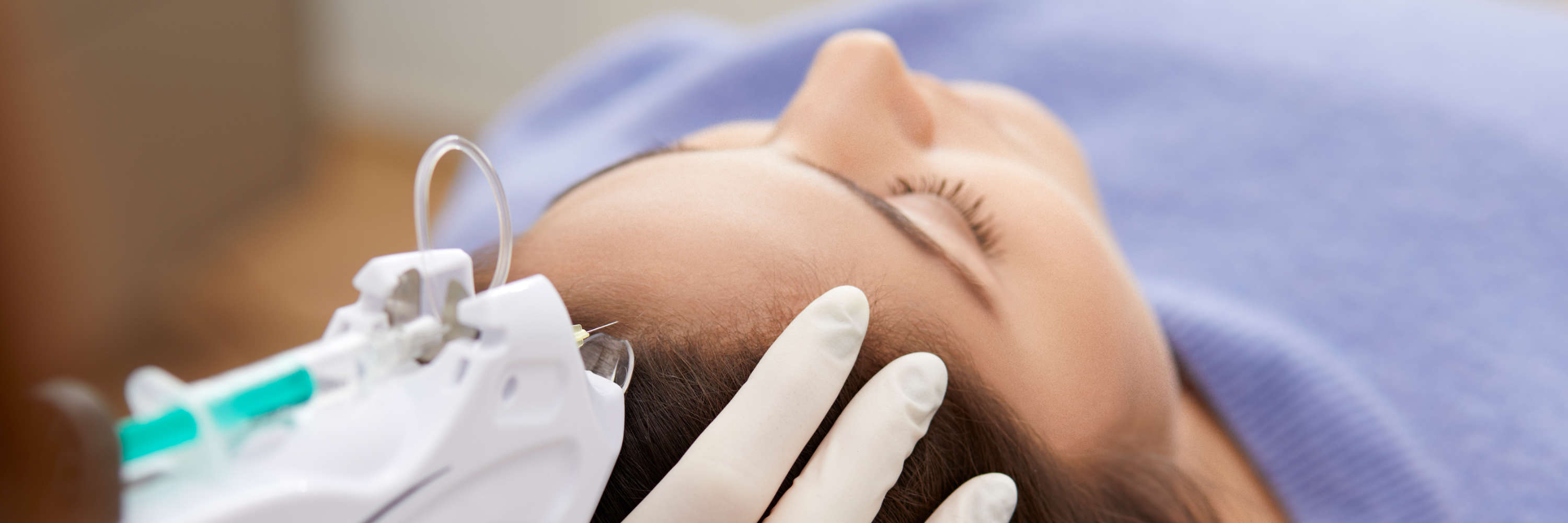 Bei einer mesotherapeutischen Behandlung liegt eine Patientin der Frankfurter Hautarztpraxis gemütlich auf der Behandlungsliege. Ein Dermatologe injiziert einen Wirkstoffkomplex direkt in die betroffene Region, um den regenerativen Prozess anzustoßen.