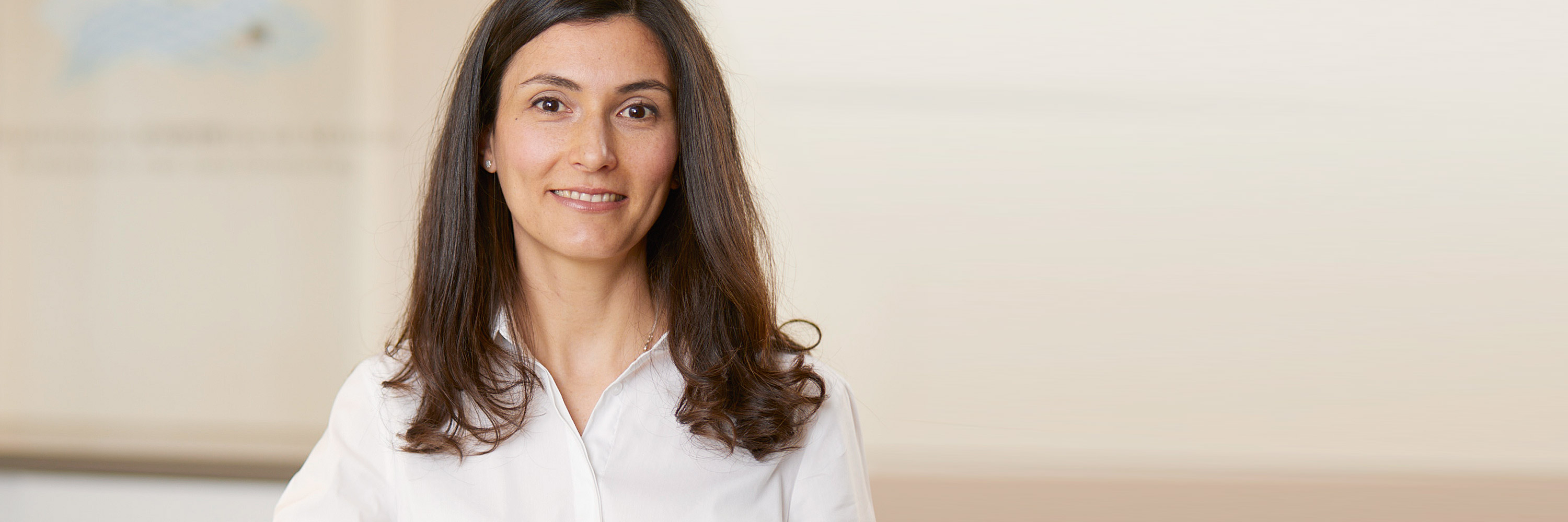 Dermatologist wears a white shirt and has long dark brown hair. She smiles, her black eyes shining. Marta González Sánchez is a specialist in skin cancer screening, tumor surgery, laser therapy, photodynamic therapy and phlebology in Frankfurt.